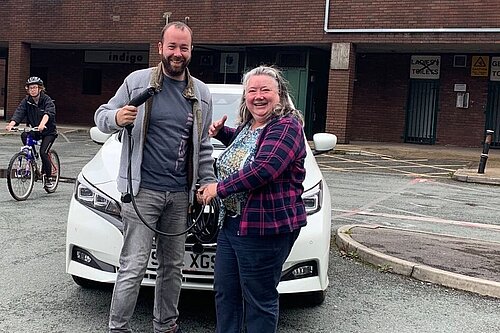 Cllrs Mark Roberts (holding an EV charger) and Angie Clark outside The Forum Theatre in Romiley